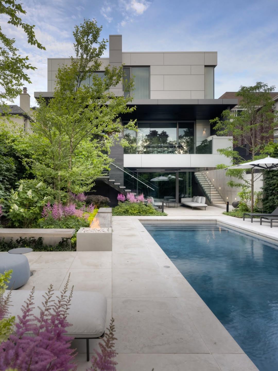 Modern backyard with a long pool, stone deck and planting